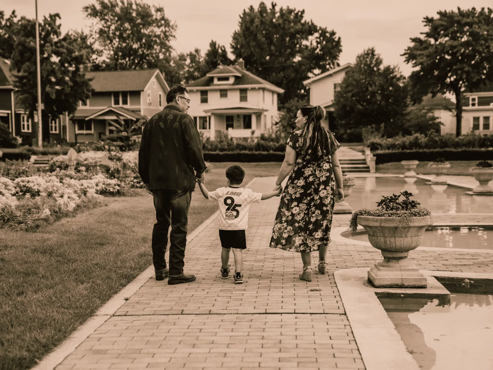 The family walking down a long garden path toward the houses