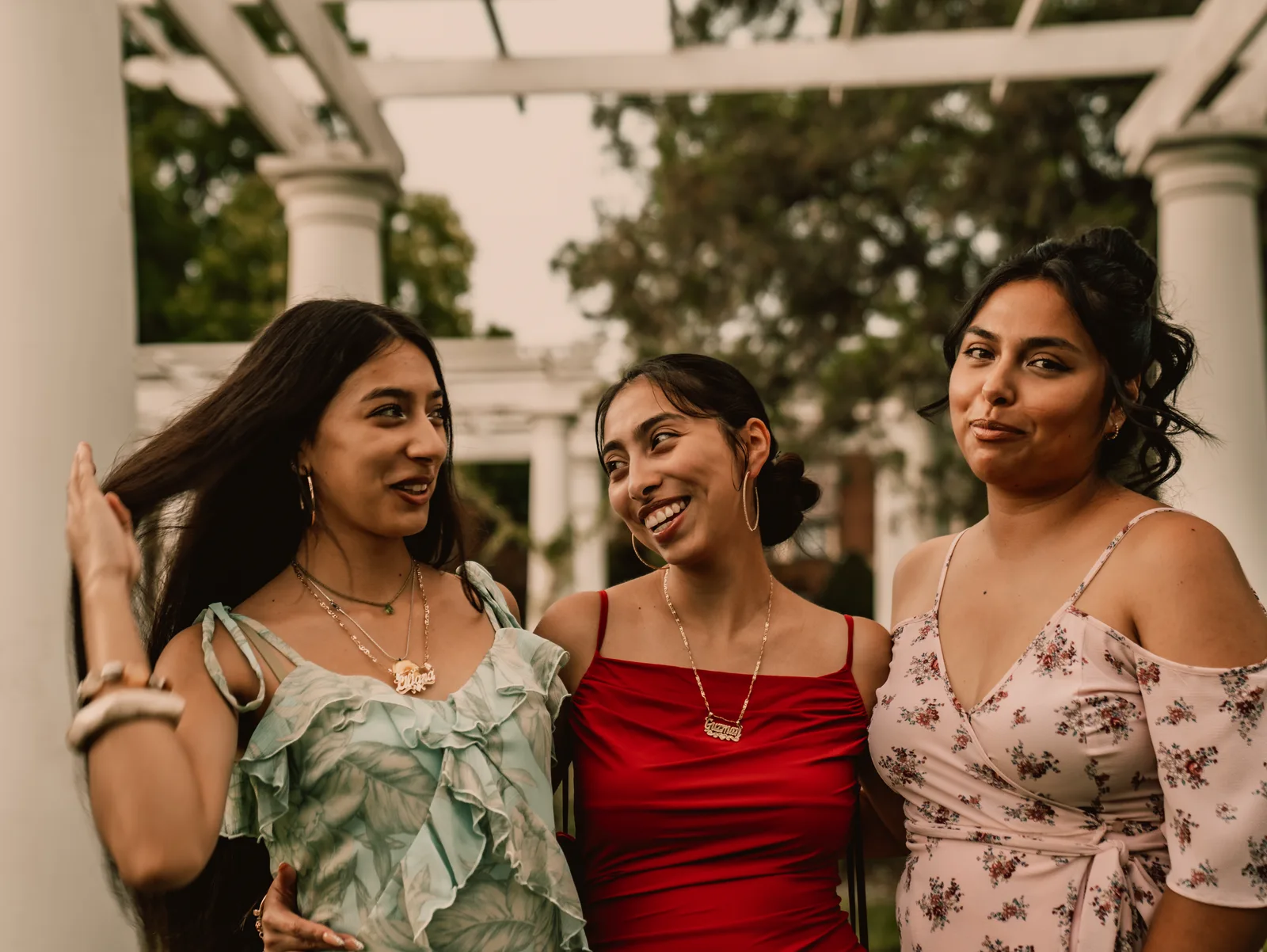 Three sisters laughing together beneath the pergola