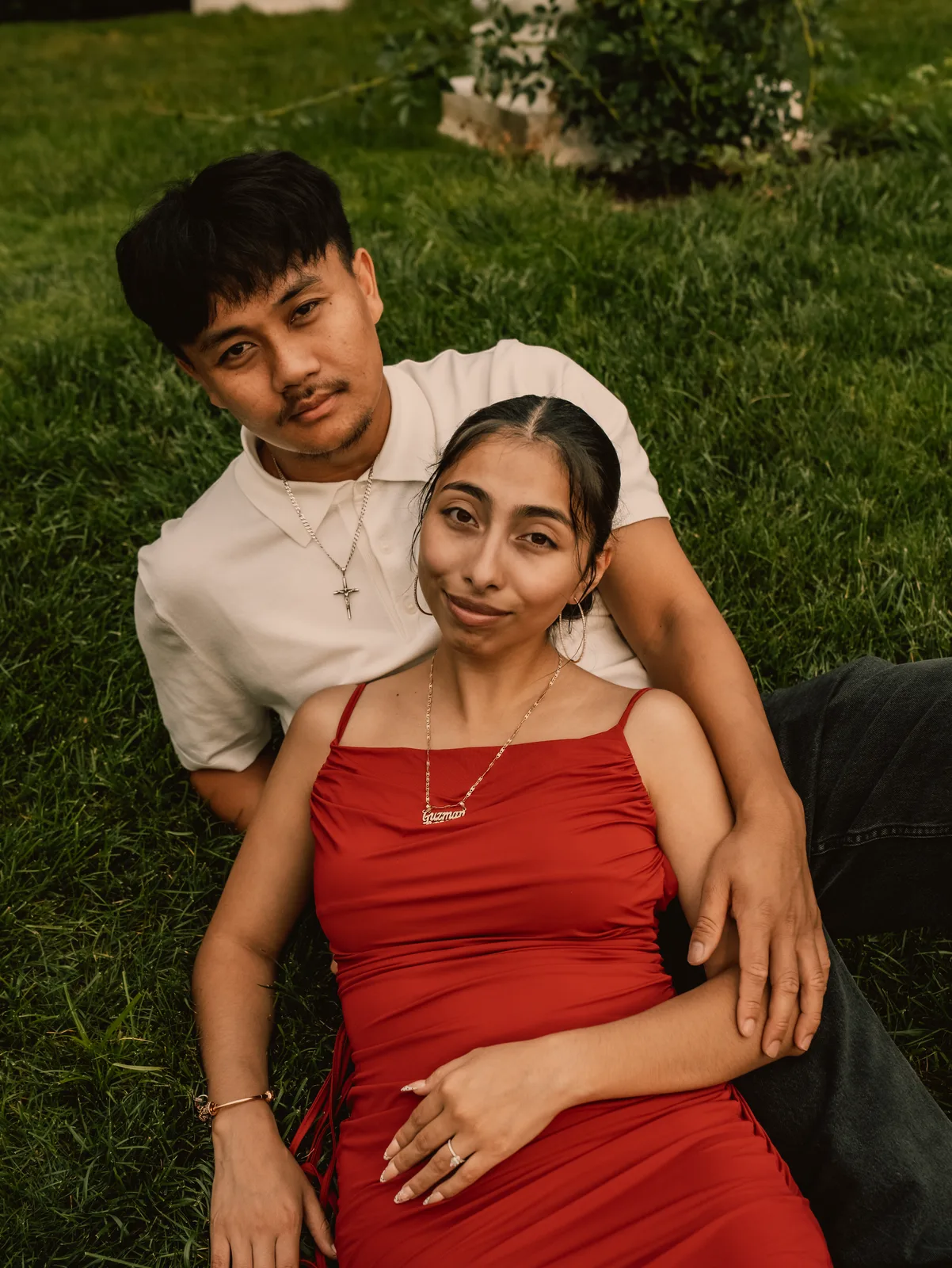 A couple sitting in the grass, he holds her from behind