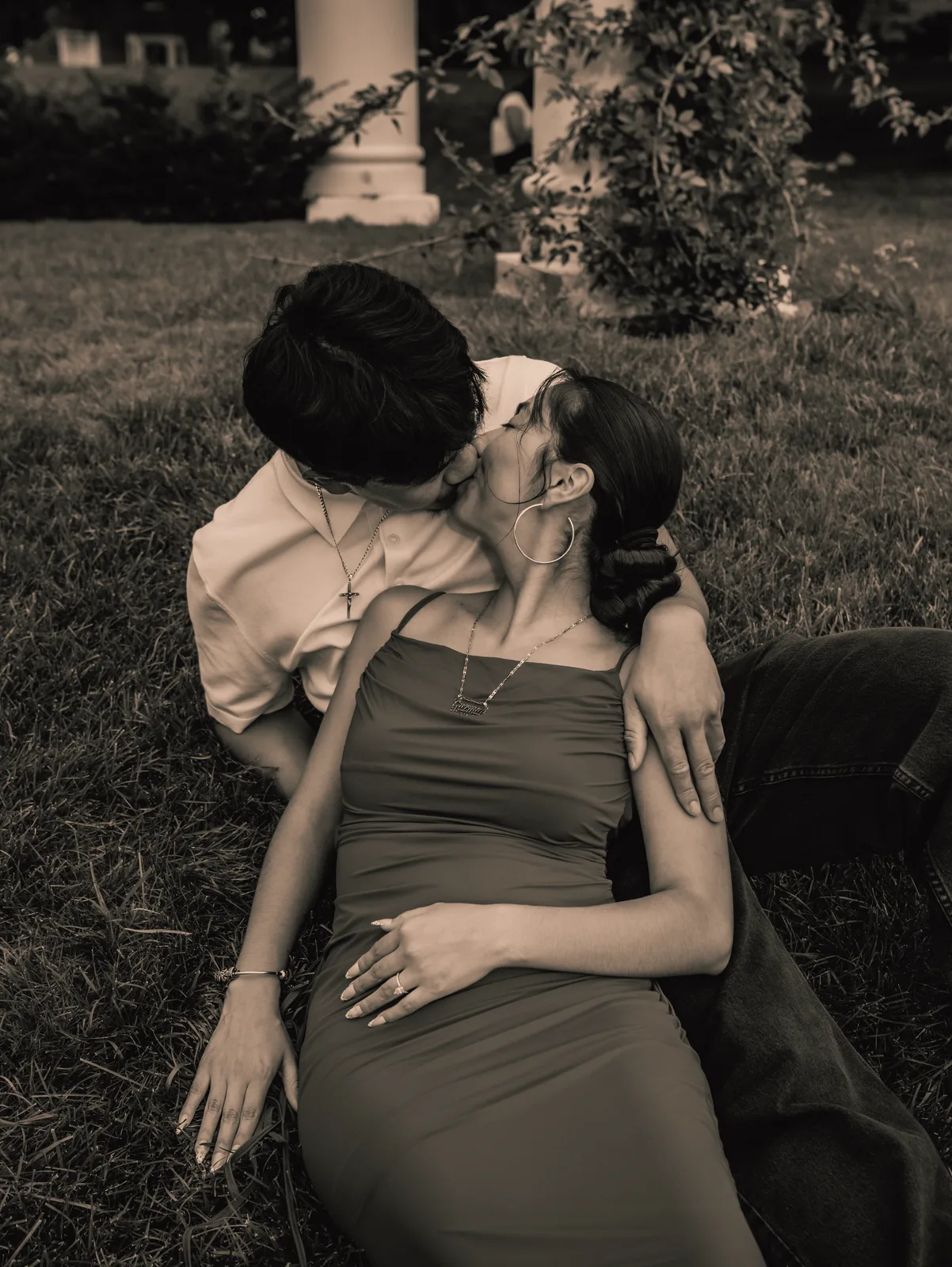 A black and white frame of the couple leaning close in the grass