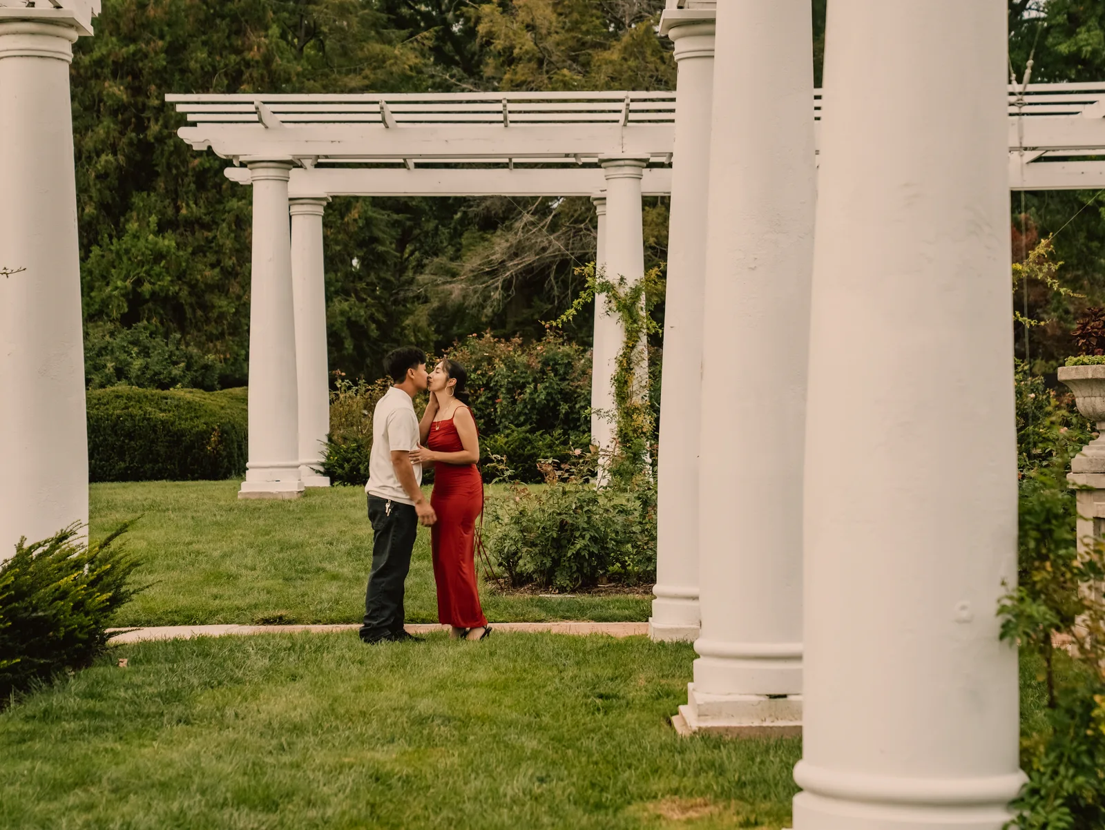 The couple embracing between the pergola columns