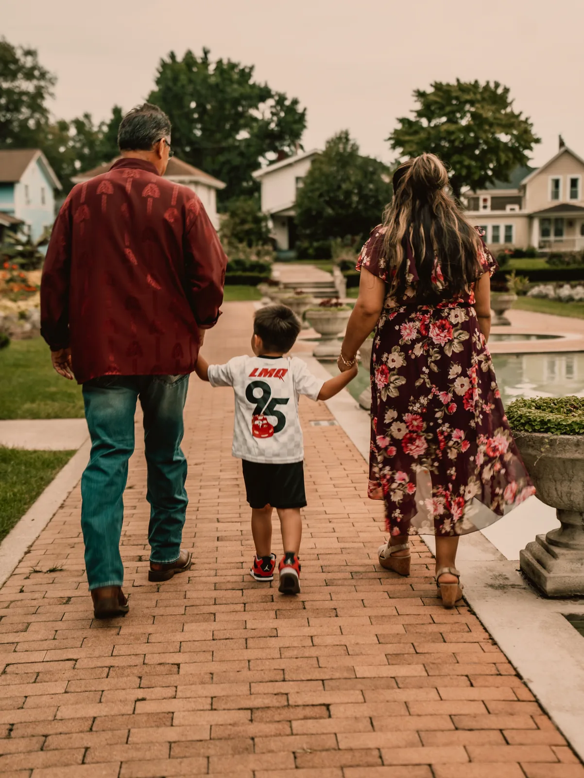Parents walking a young boy down a brick path