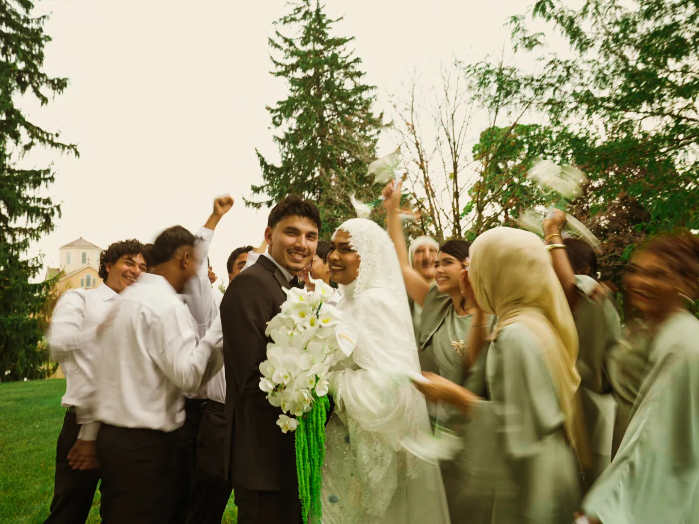 The newlyweds smiling among friends during an outdoor celebration