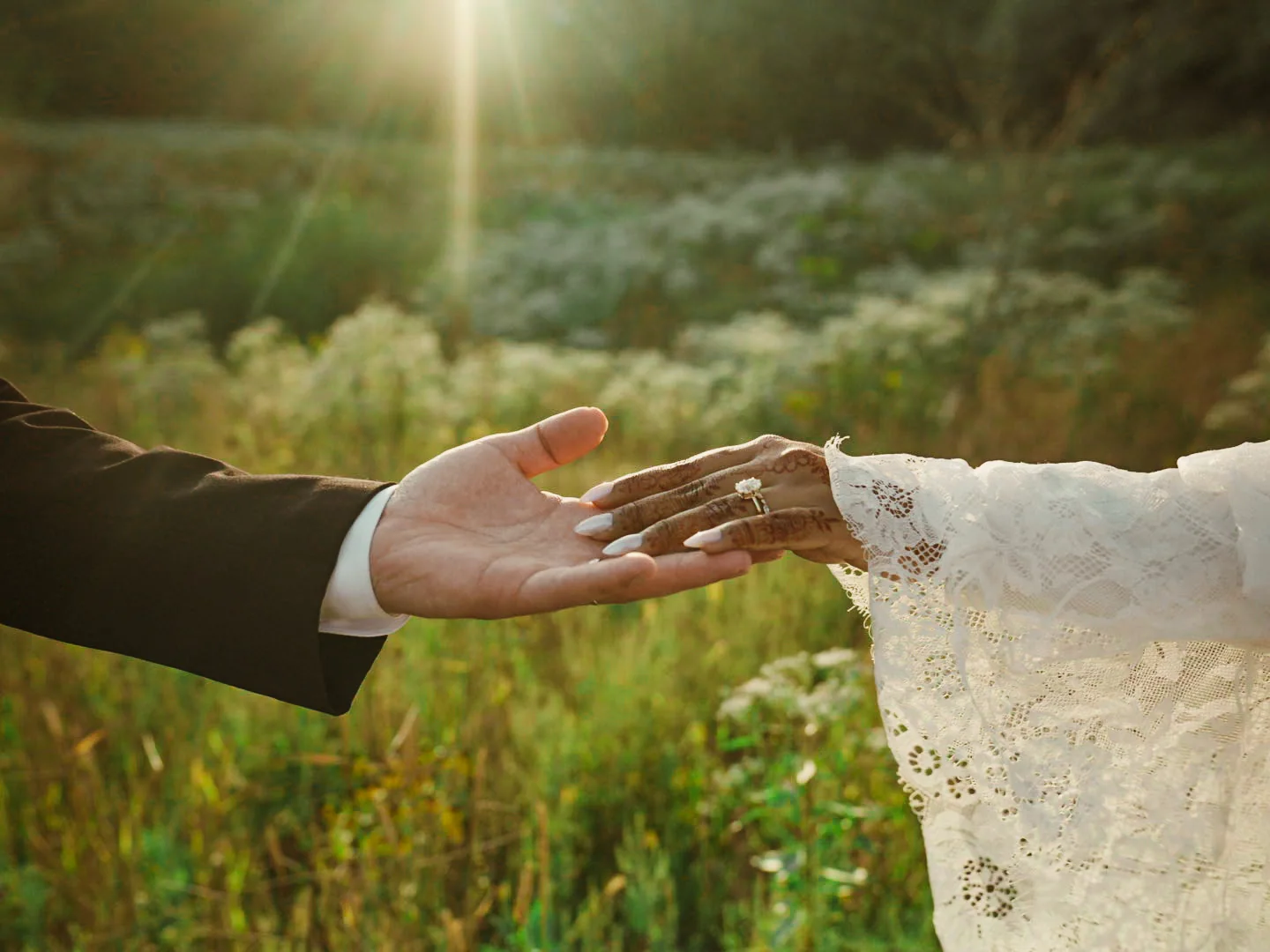 The couple reaching toward each other with wedding rings visible